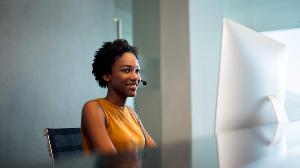 A woman working on a reception desk, wearing a headset