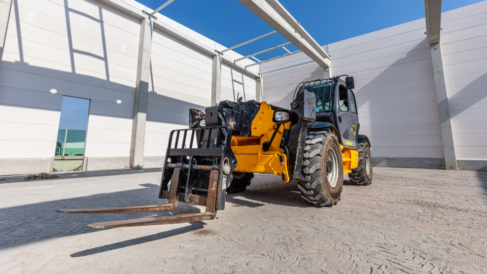 A telehandler inside the frame of a building under construction