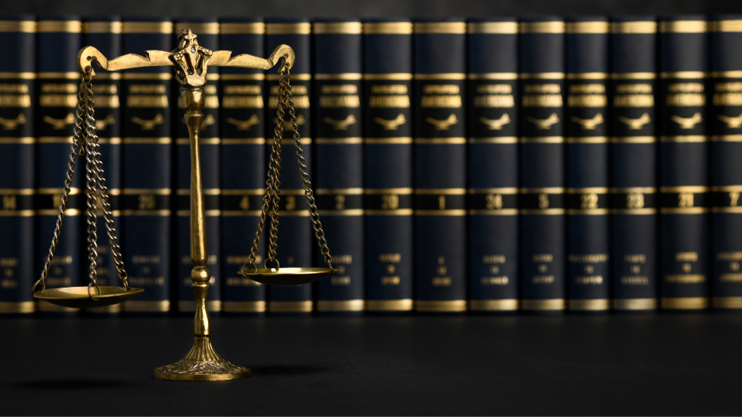 An image of a gold set of scales in front of many black and gold books