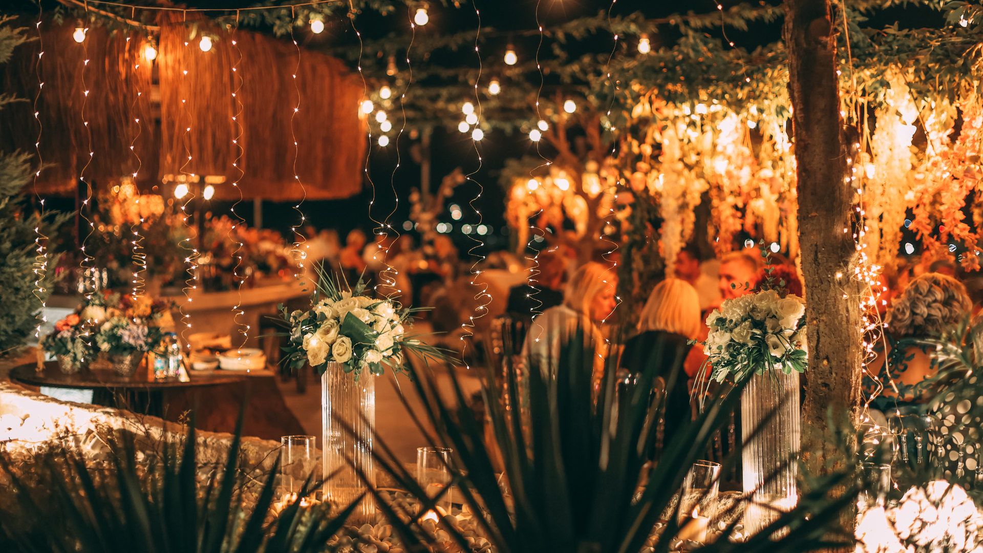 An image looking through a window of a restaurant at christmas time. The restaurant is decorated with christmas slights and ornaments, and customers are sat around tables in the background