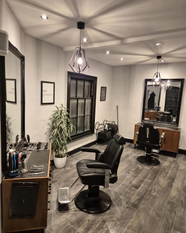 The upstairs level of Attic Brew, which is a working barbershop. There are leather barber chairs and wooden benches against the walls, with barber equipment on the benches