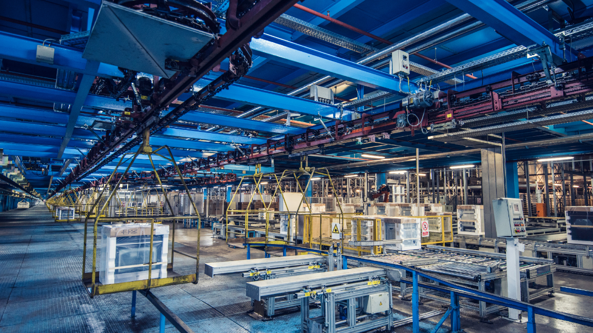 The inside of a large factory, with production lines and materials around the room 