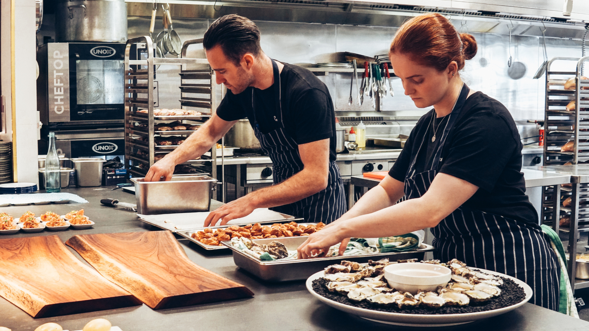 Two chefs, one male and one female, working in a kitchen. They are preparing ingredients to be used in meals