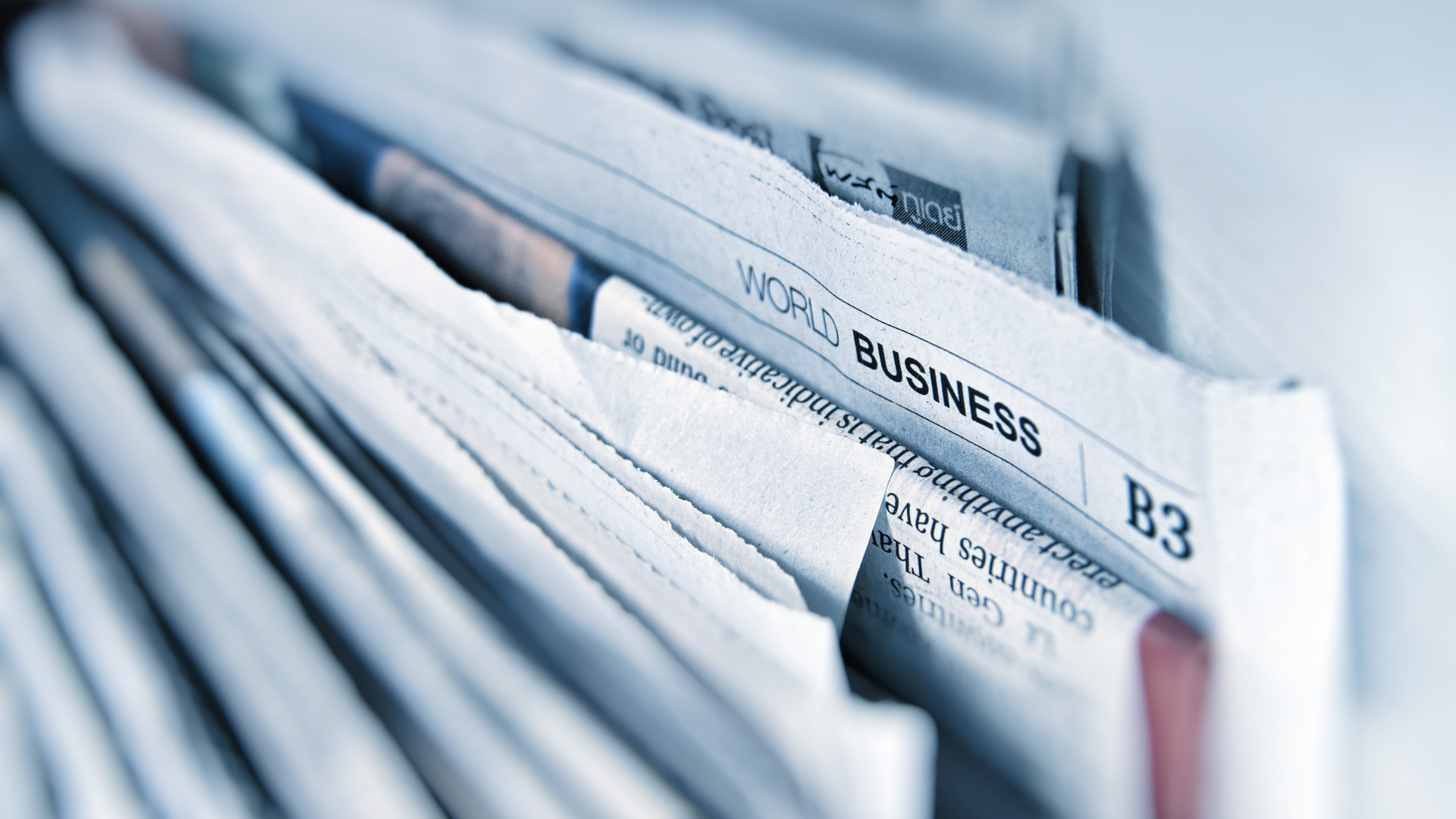 A close-up of a stack of newspapers. The words "World Business" are visible.