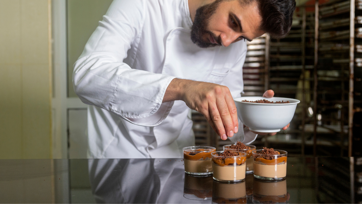 A chef adding garnish to four chocolate dessert dishes