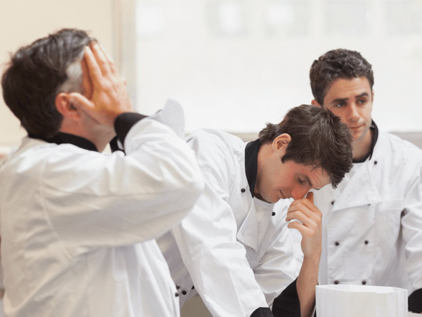 3 Chefs dressed in chef's whites looking tired