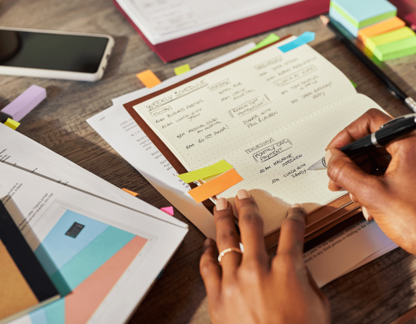 Several documents with post-it notes and schedules on a desk