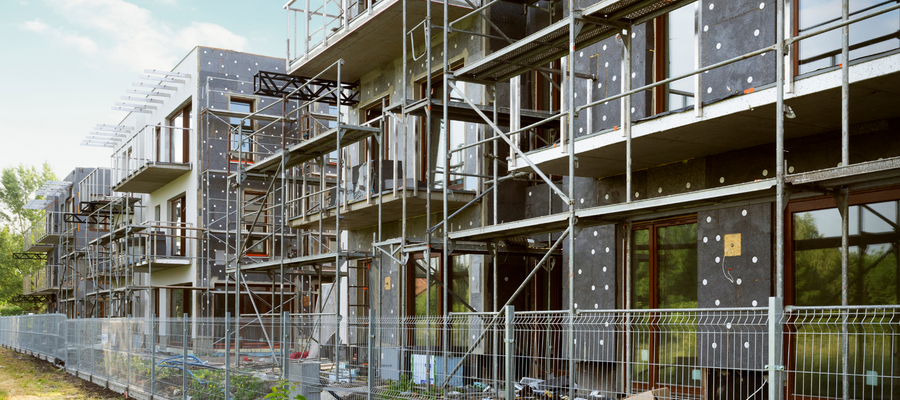 An image of modern homes under construction. They are made of prefabricated panels, and have scaffolding around them