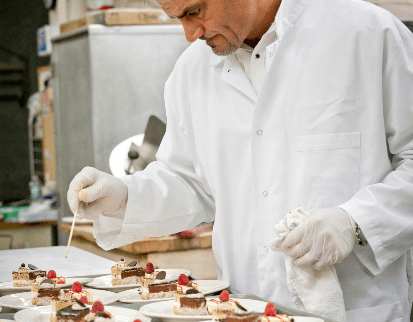 A Pastry Chef putting the finishing touches on several dessert dishes