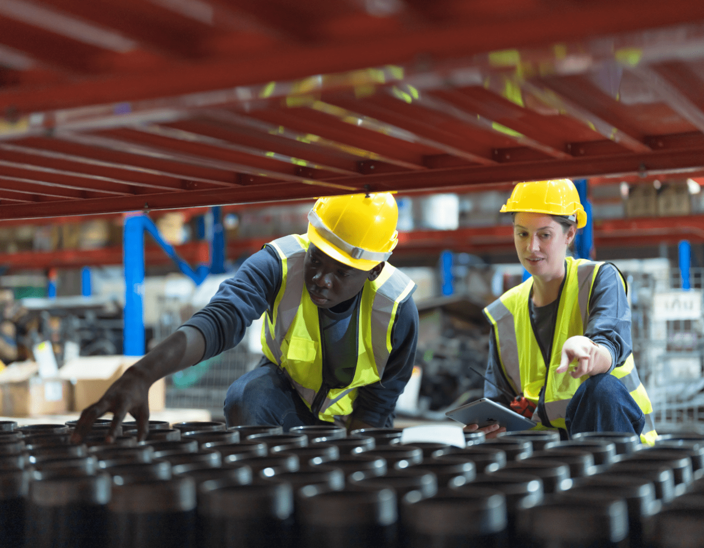 Two workers in safety wear inspecting a batch of products in a warehouse