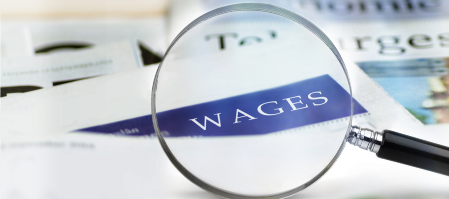 An image of a magnifying glass looking at the word "Wages" on a piece of paper