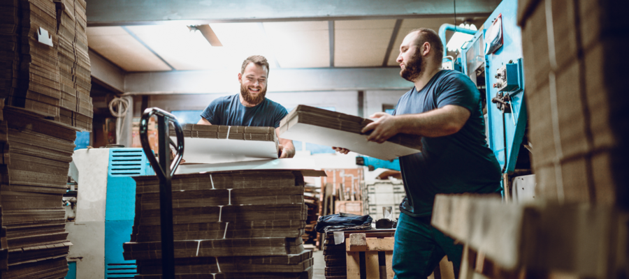 Two men working in a factory at night. They are loading products on to palletts.