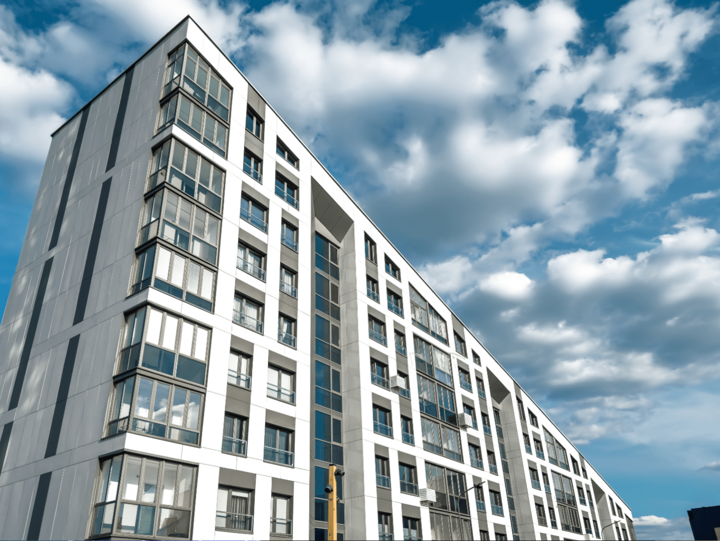 A low angle image of a modern apartment block against a blue sky