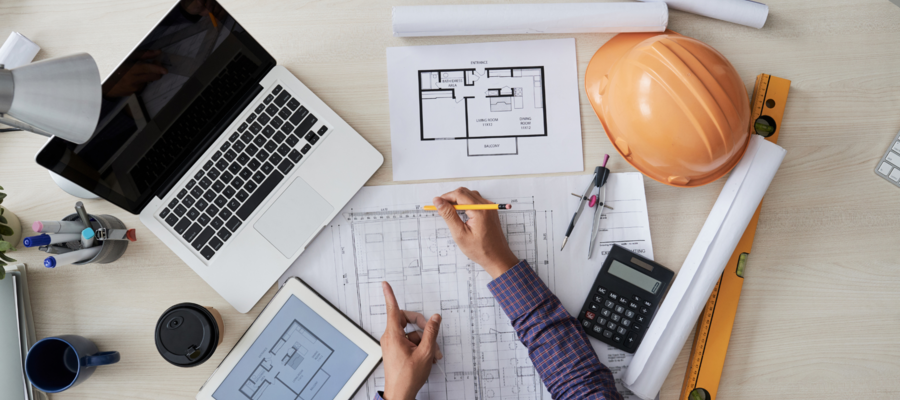 A person examining structural drawings on a desk