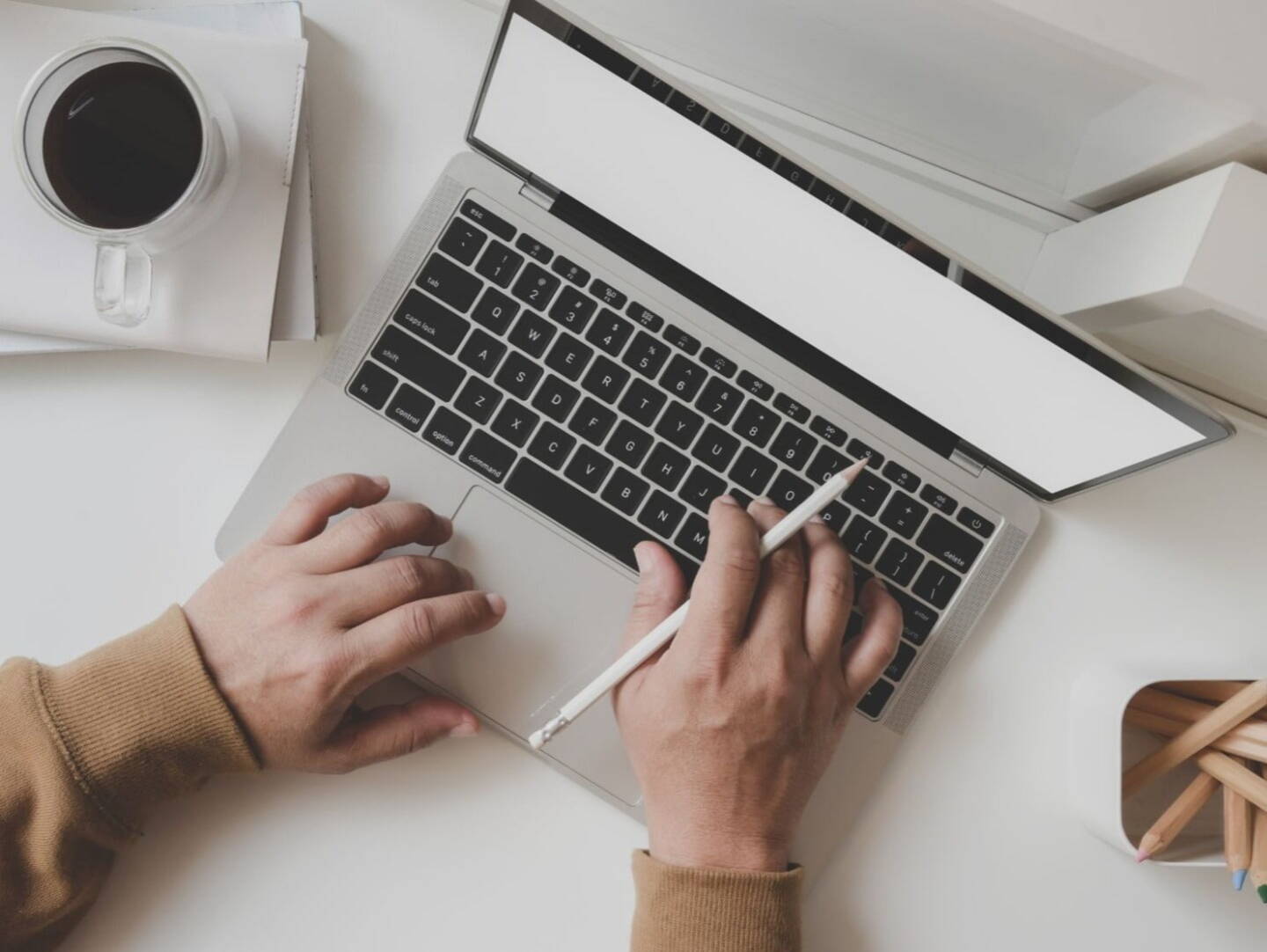 A laptop on a desk with a cup of coffee