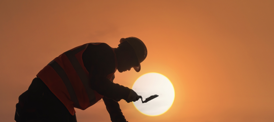 A man working on a construction site against a sunset