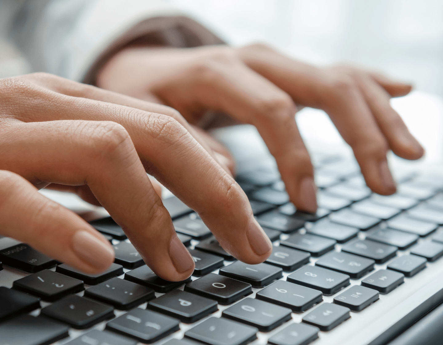 A close-up image of fingers typing on a laptop keyboard