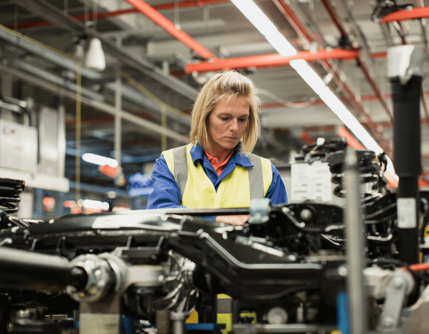 A woman in a high-visibility jacket working in a manufacturing environment